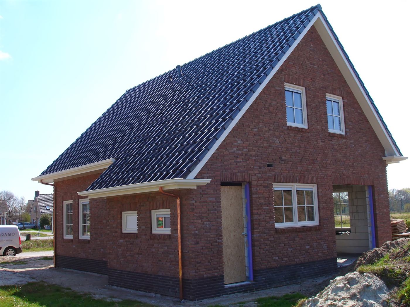 De woning in aanbouw, bijna klaar, onder een blauwe lucht