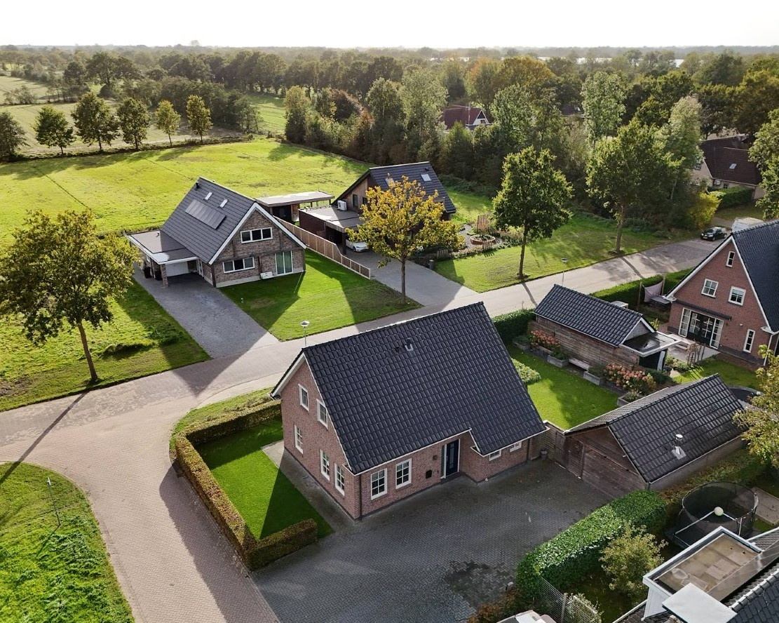 Luchtfoto van De Swannepôle 14 op de hoek, met weilanden en bomenrijen erachter