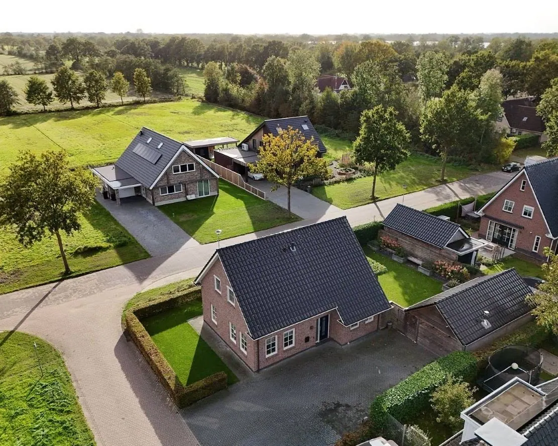 Luchtfoto van De Swannepôle 14 op de hoek, met weilanden en bomenrijen erachter