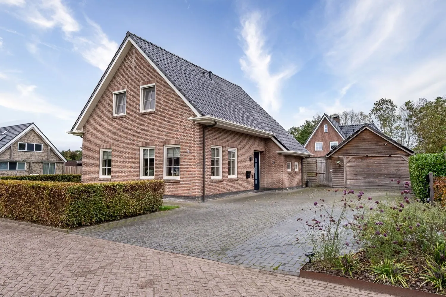 Voorzijde van de woning met oprit, onder een blauwe lucht